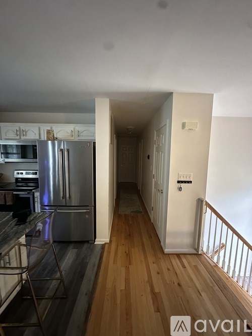 A kitchen with a stainless steel refrigerator and wooden floors.