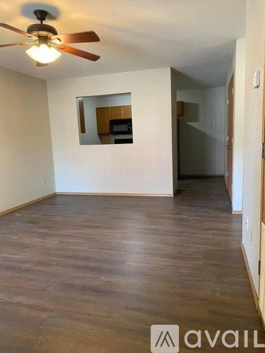 A room with a ceiling fan and wooden flooring.