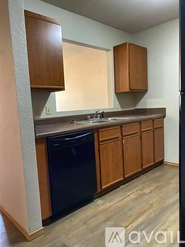 A kitchen with wooden cabinets and a black dishwasher.