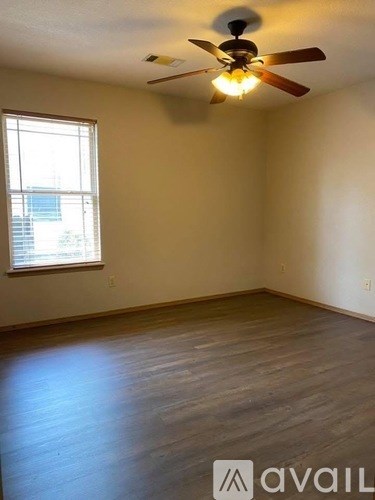 A room with a ceiling fan and wooden flooring.