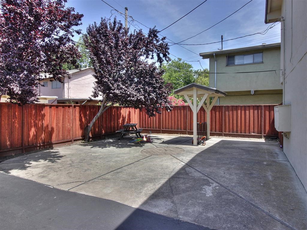 a backyard with a red fence and a tree and a driveway