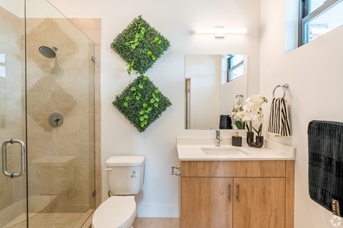 A bathroom with a green plant on the wall.