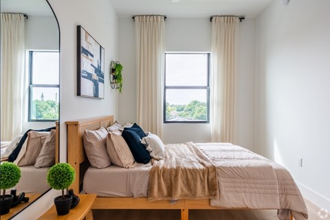 A bedroom with a large bed and a mirror on the wall.