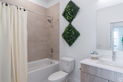 A bathroom with a green plant on the wall.