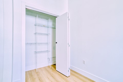 A white door is open to a room with a white wall and a white floor.