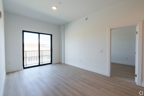 A room with a sliding glass door and a wooden floor.