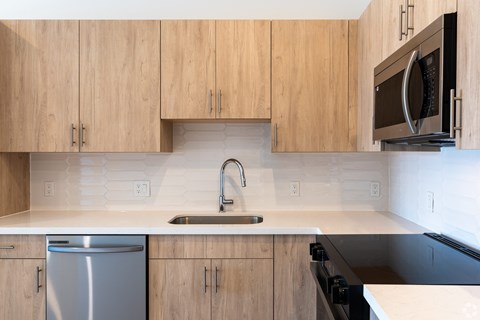 A kitchen with wooden cabinets and a stainless steel dishwasher.