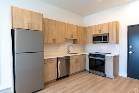 A kitchen with a refrigerator, microwave, oven, and sink.