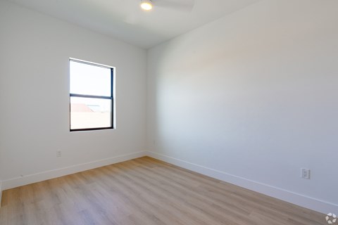 A room with a window and wooden flooring.