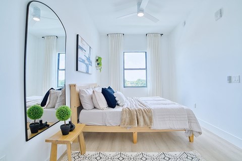 A bedroom with a bed, a mirror, and a ceiling fan.