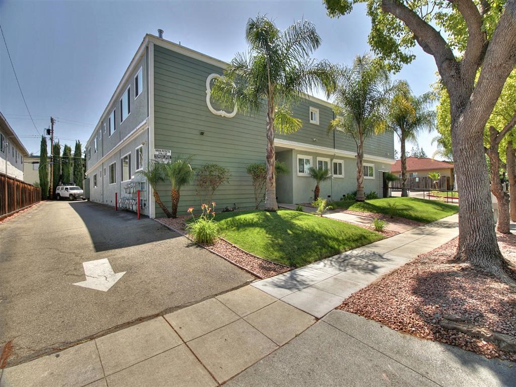 A street view of a green building with a white arrow on the road.
