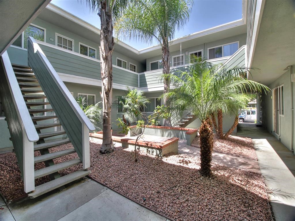 A patio with a bench and a tree in front of a building.