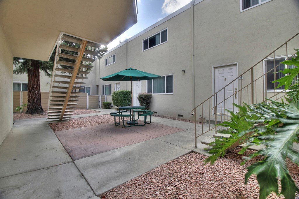 A patio with a table and chairs and a green umbrella.