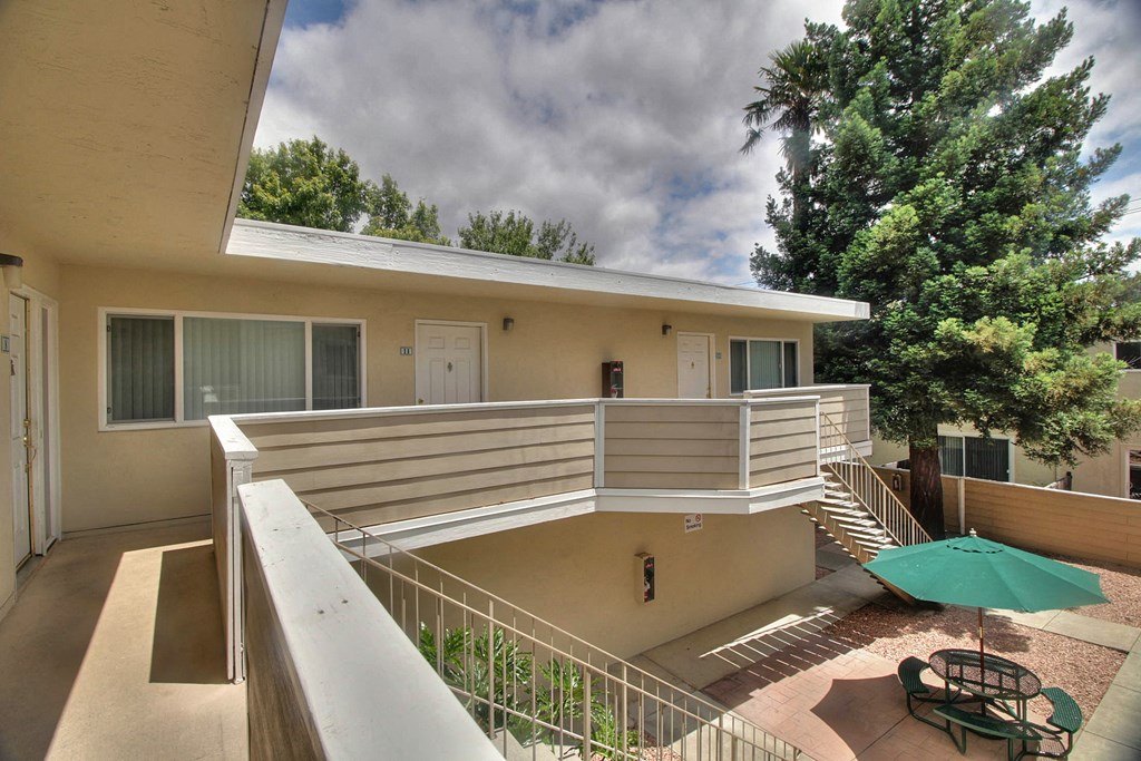 A balcony with a table and chairs overlooking a courtyard.