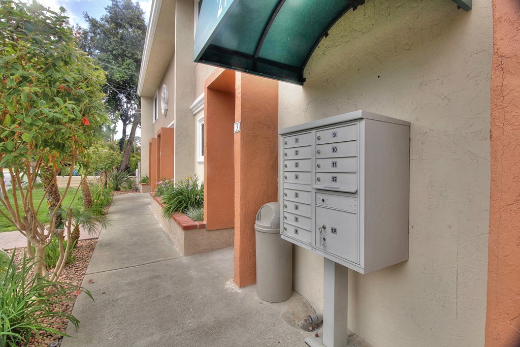 A grey mailbox is on the side of a building with a green awning.