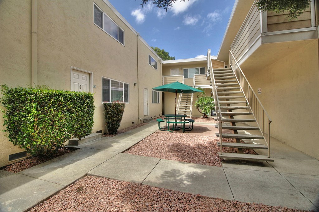 A patio with a staircase and a green umbrella.