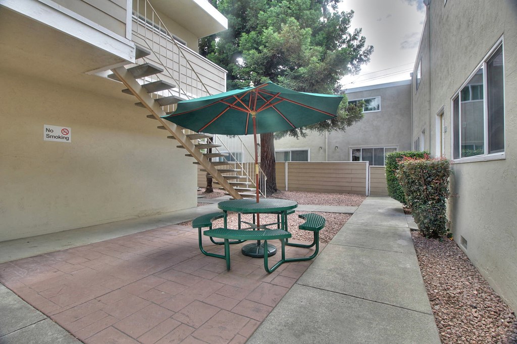 A patio with a table and chairs under a green umbrella.