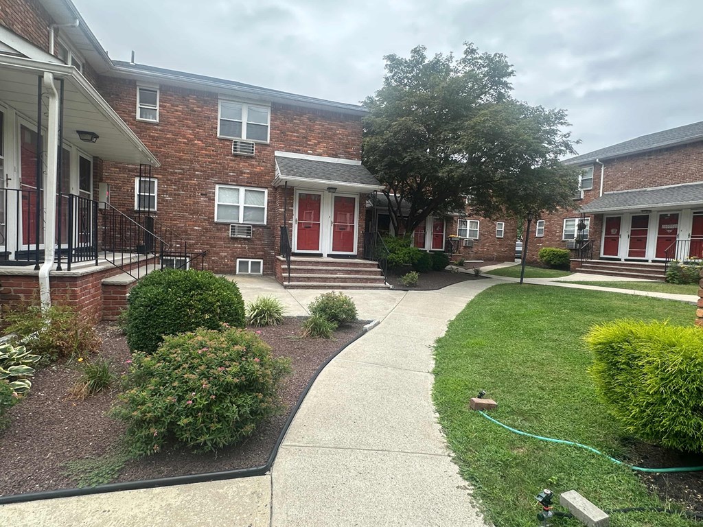 A brick building with a red door and a tree in front.