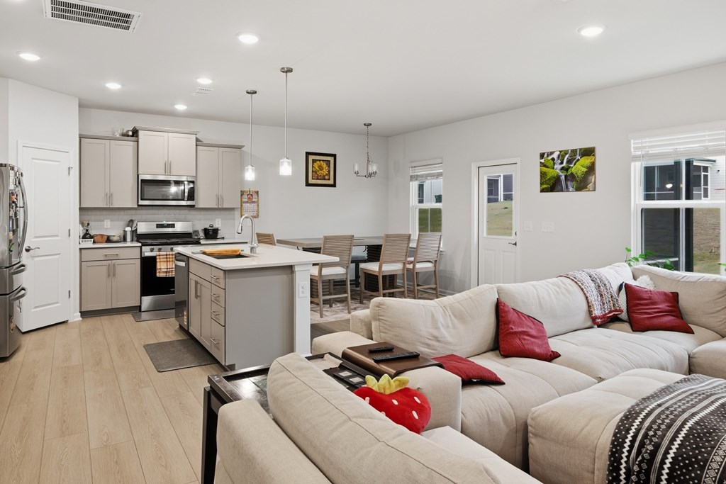 A modern living room with a kitchen in the background.