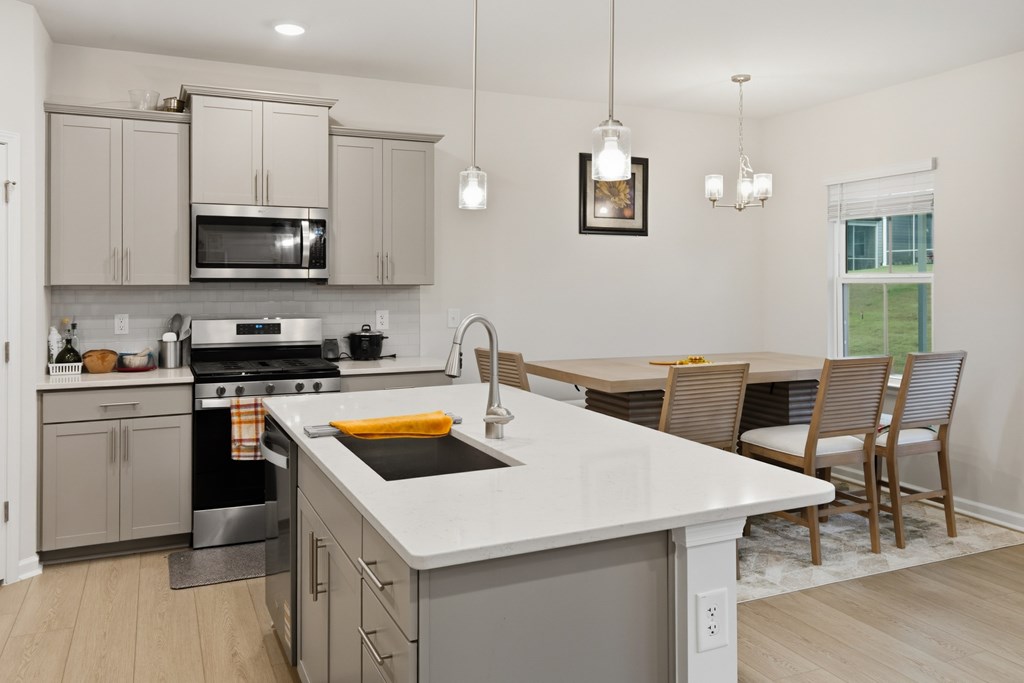 A kitchen with a white counter top and grey cabinets.
