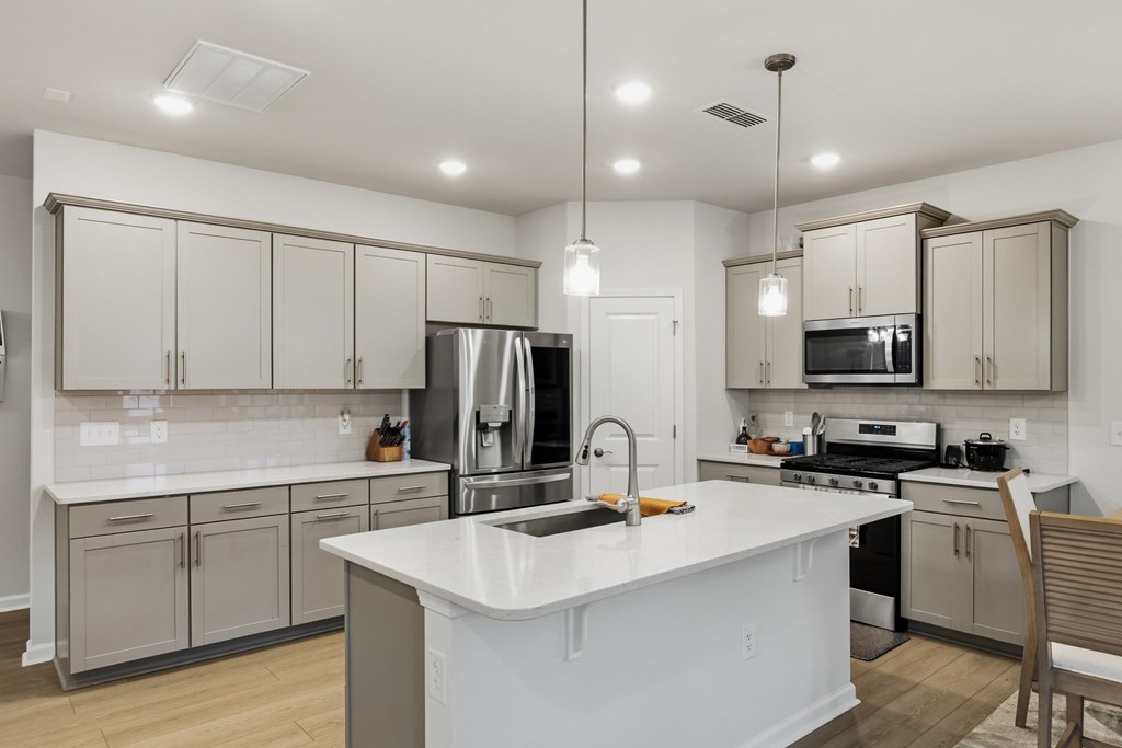 A modern kitchen with a white island and stainless steel appliances.