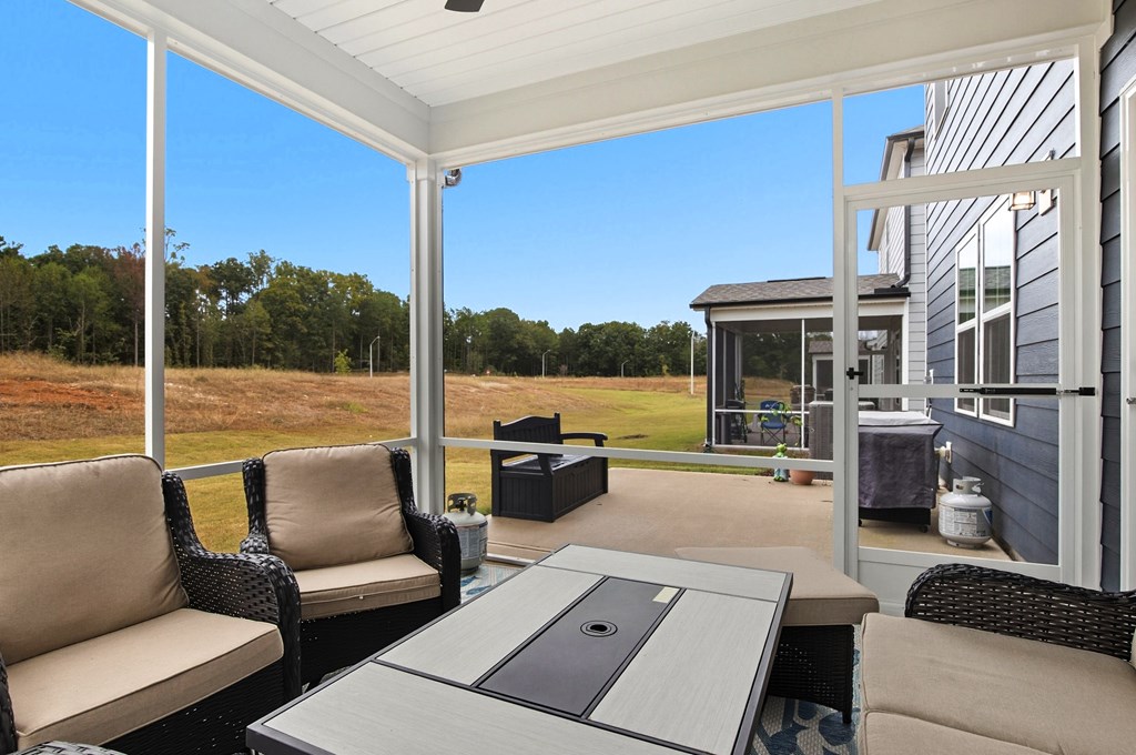 A patio with a table and chairs overlooking a grassy field.