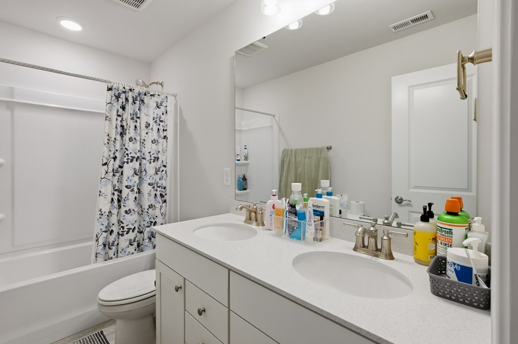 A bathroom with a white sink, toilet, and shower curtain.
