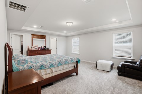 A bedroom with a bed, chair, and window.