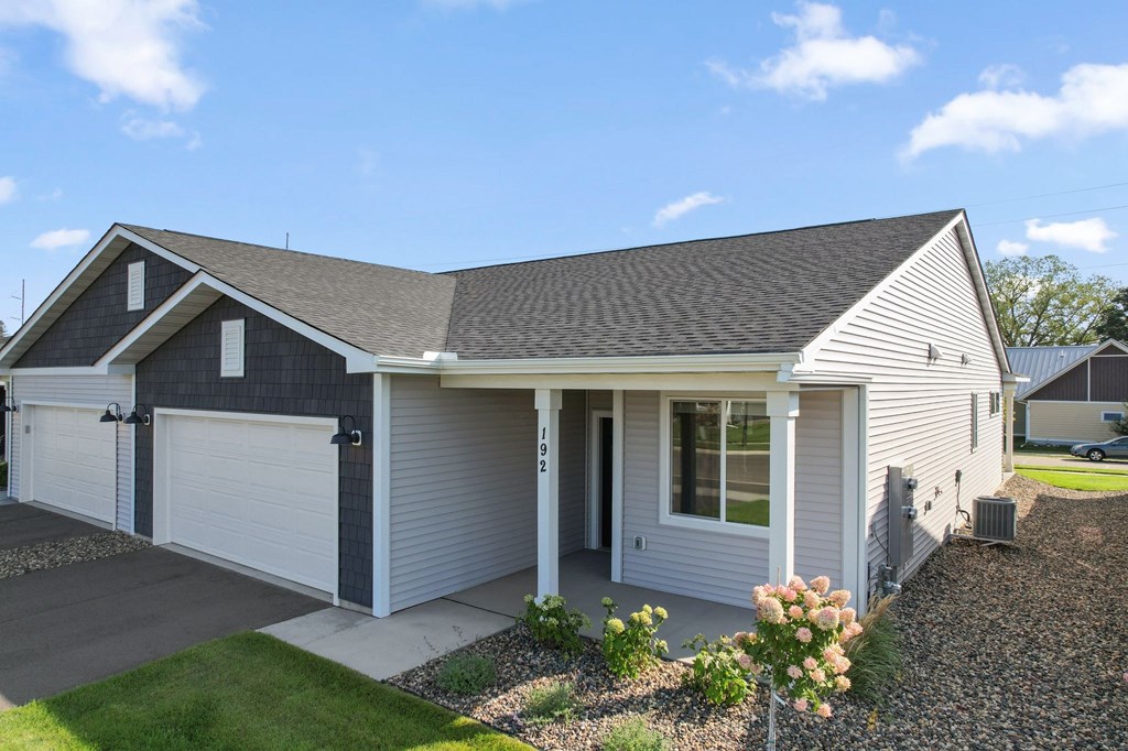 A house with a grey roof and white garage doors.