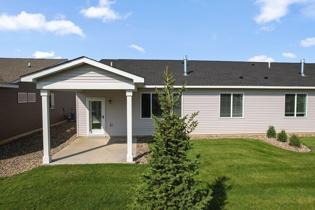 A house with a covered entryway and a green lawn.