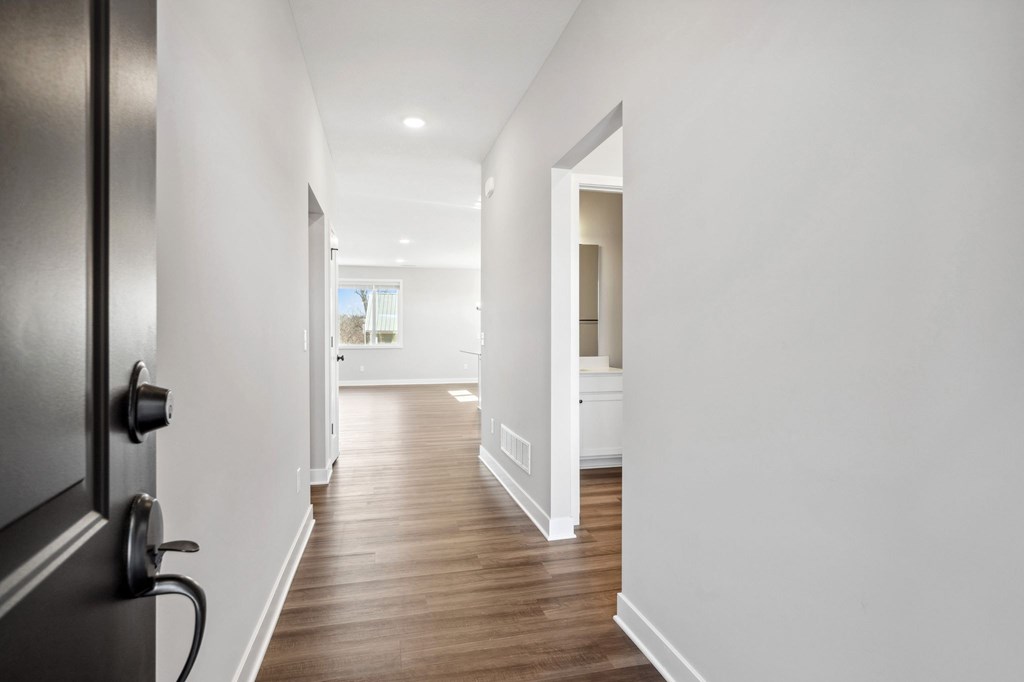 A long hallway with a black door on the left.