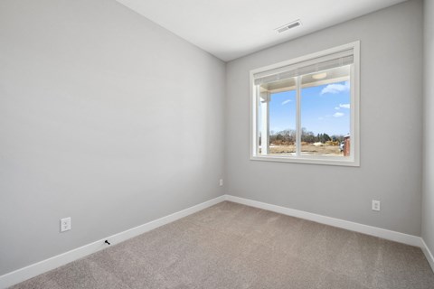 A room with a window showing a view of trees and a blue sky.