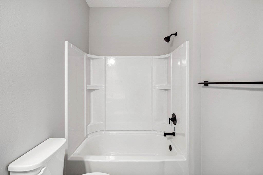 A white bathroom with a toilet, bathtub, and shower.