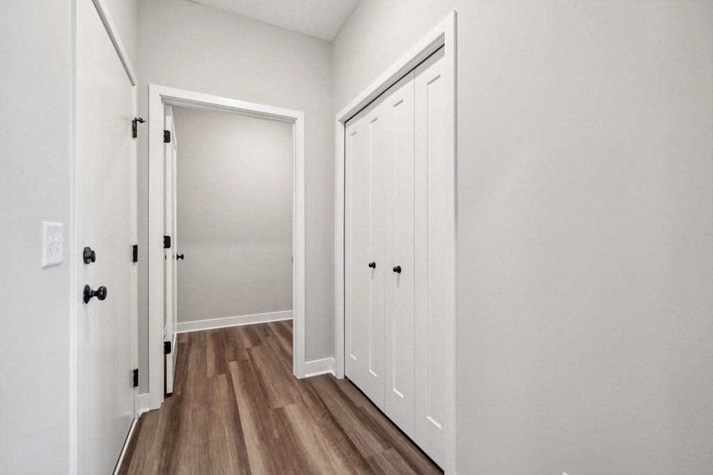 A white door with a black handle is open to a hallway.