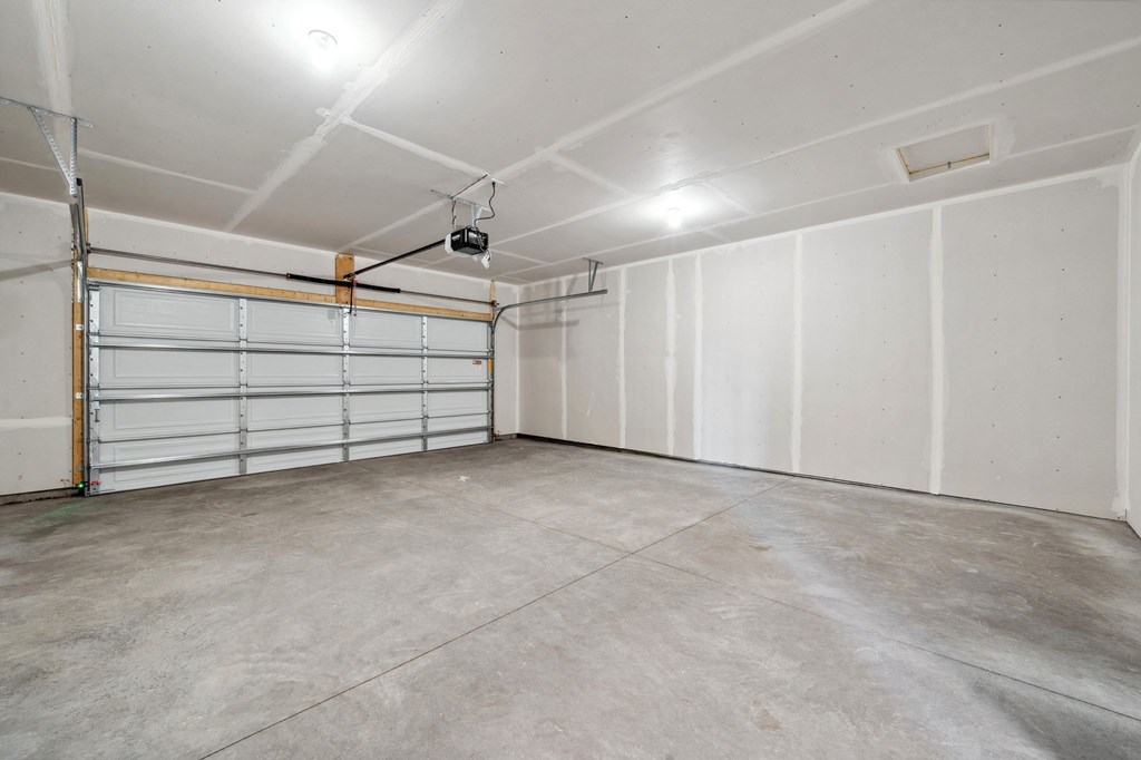 A spacious garage with a closed white door and a concrete floor.