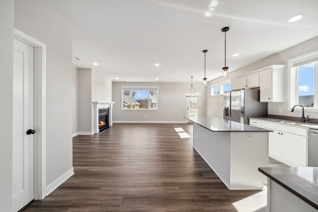 A modern kitchen with white cabinets and a wooden floor.