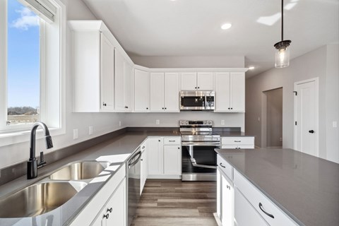 A modern kitchen with white cabinets and stainless steel appliances.