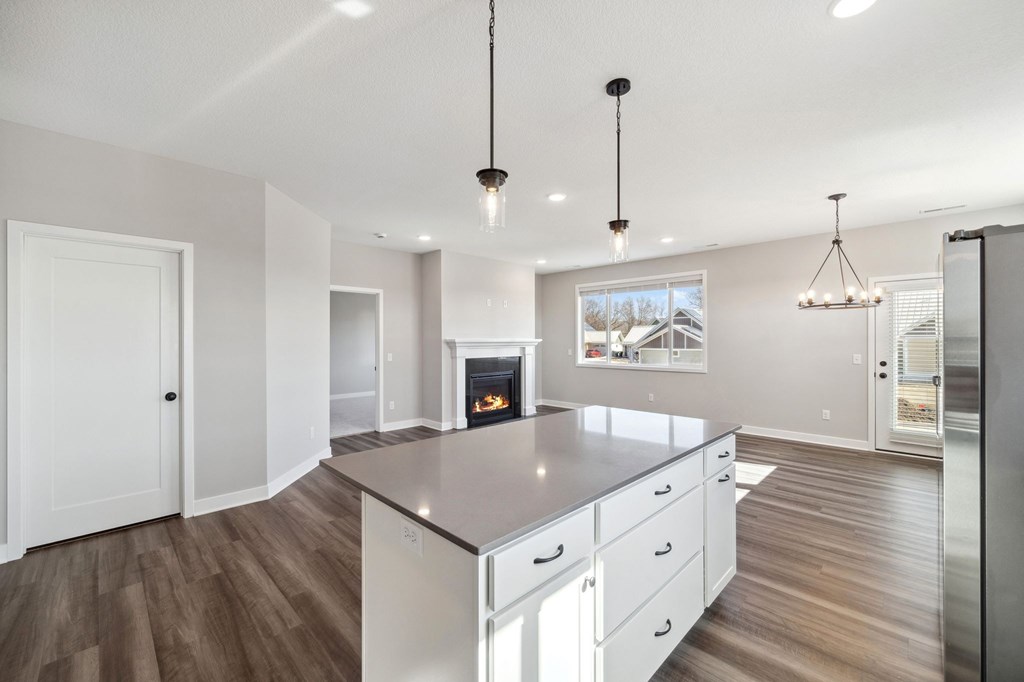 A modern kitchen with a large island and a fireplace in the background.