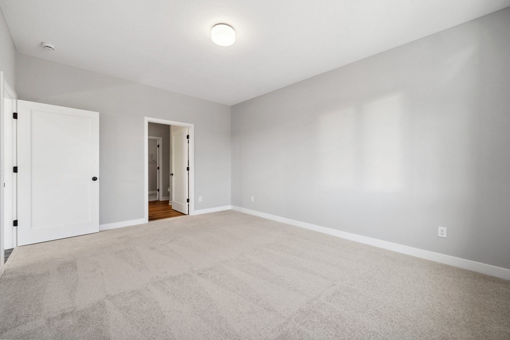 A room with a carpeted floor and a white door.