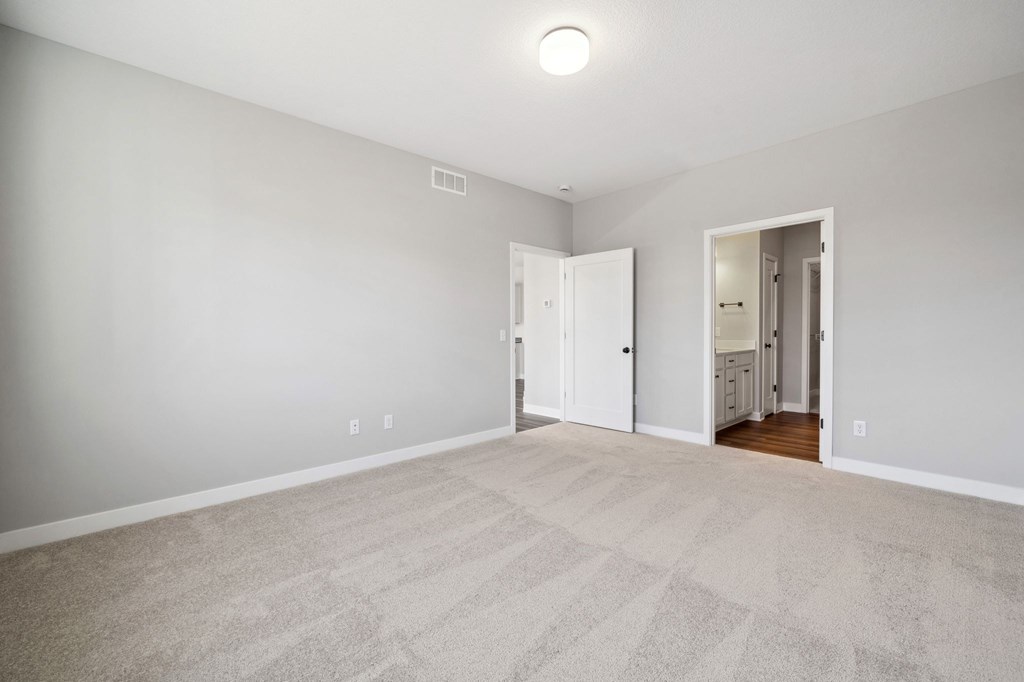 A room with a carpeted floor and a white door.