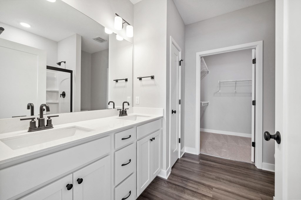 A white bathroom with a double sink and a large mirror.