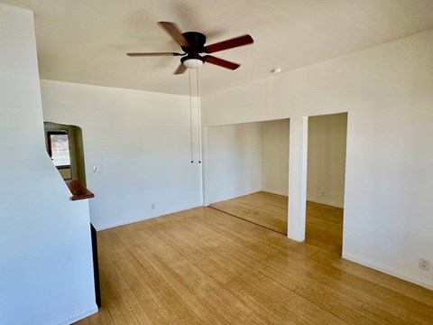 A room with a ceiling fan and wooden flooring.