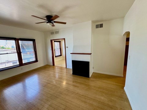 A room with a ceiling fan and wooden flooring.