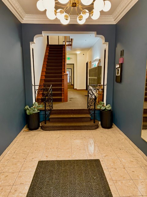 A hallway with a staircase and a chandelier.