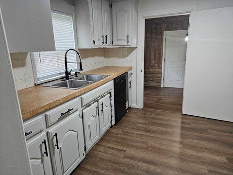 A kitchen with white cabinets and a brown countertop.