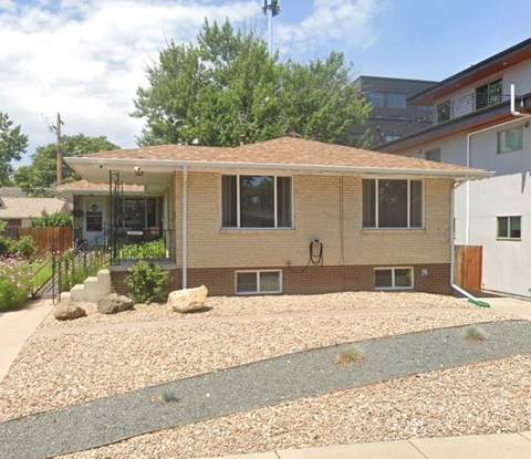 A house with a brown roof and a gravel driveway.