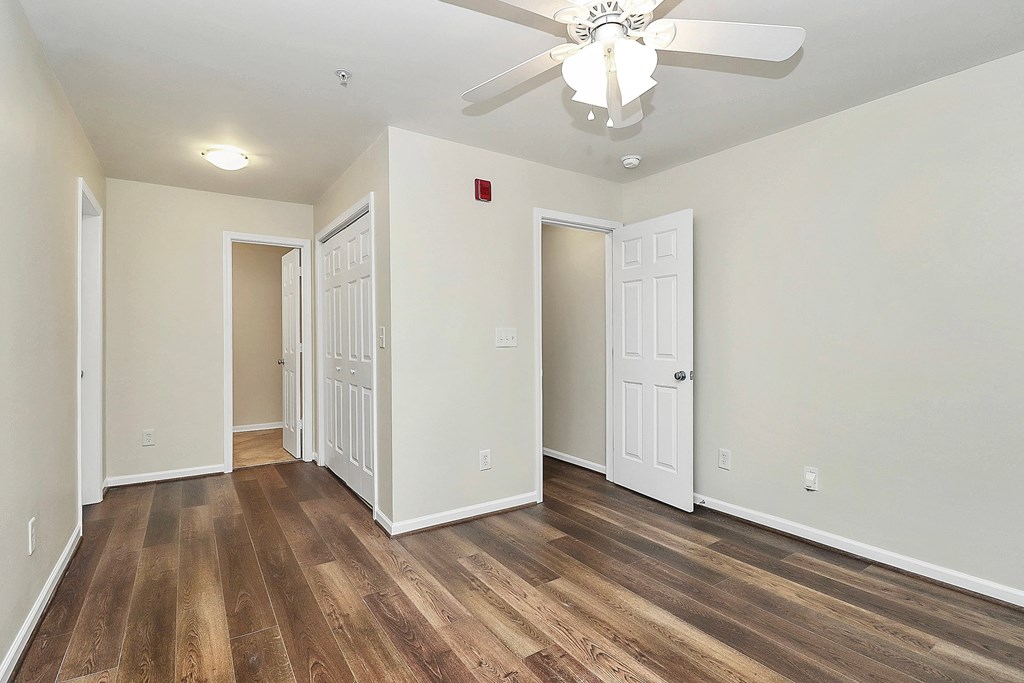 A room with a ceiling fan and wood flooring.
