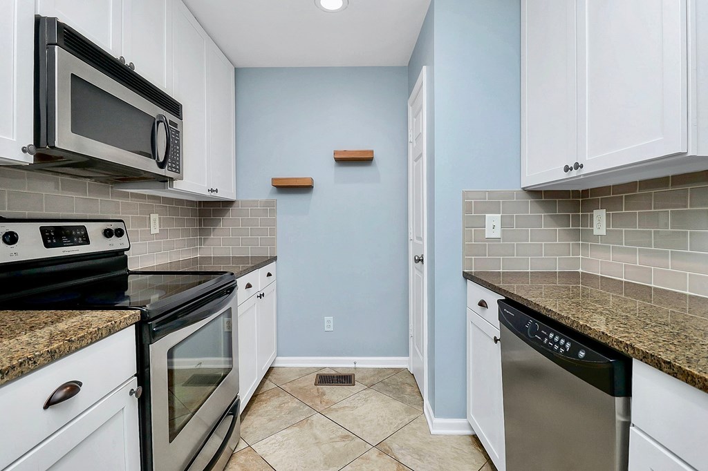 A kitchen with white cabinets and a granite countertop.