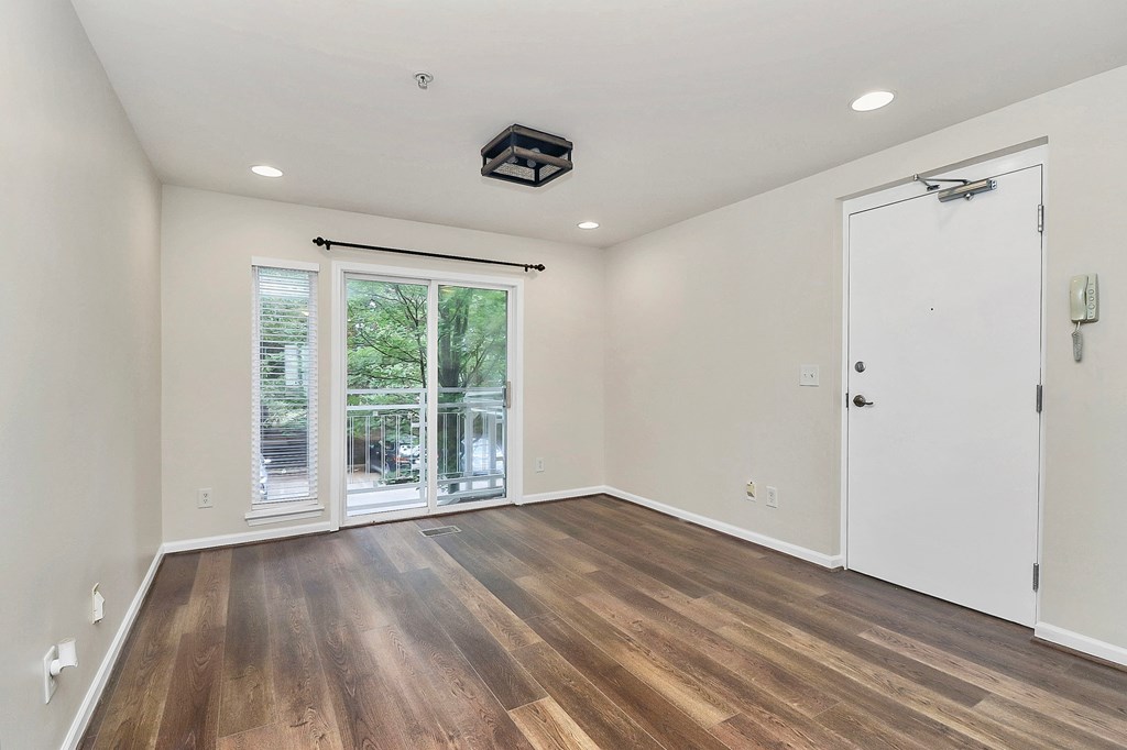 A room with wooden floors and a sliding glass door leading to a patio.