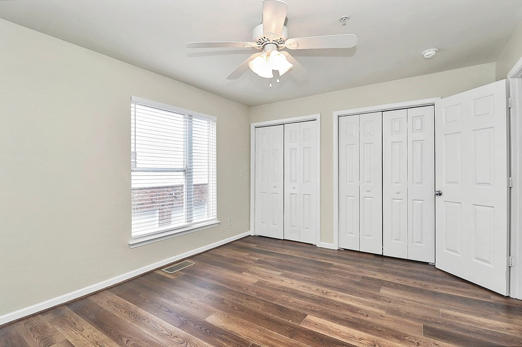 A room with a ceiling fan and three white doors.